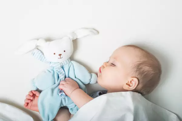 Baby sleeping next to a toy bunny.